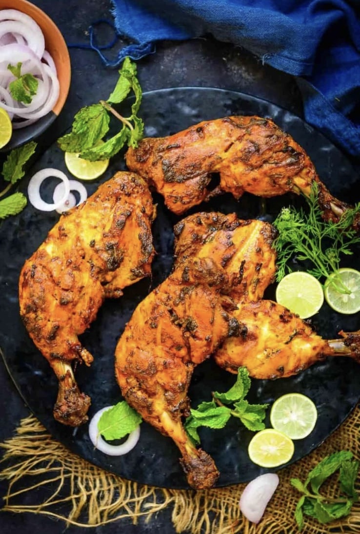 Tandoori chicken quarters on a black plate